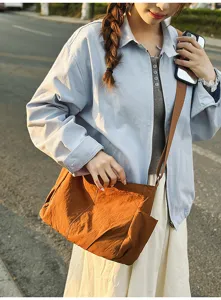 Details of the brown nylon crossbody bag worn by model, showing large capacity and side pockets.