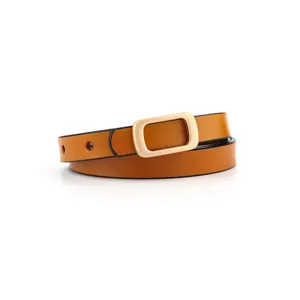 Close-up detail of women's thin caramel leather belt with minimalist gold rectangle buckle.