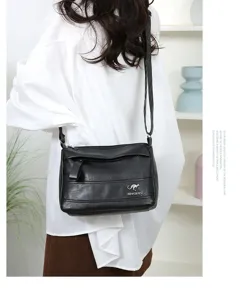 Close-up detail of the black leather shoulder crossbody bag with metal kangaroo logo accent.