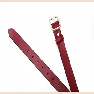 Red leather belt close-up detail, showing the refined gold metal buckle and multiple holes.