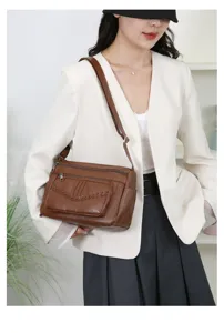 Detailed view of the brown leather shoulder bag with multi-pocket design and chic braided texture.