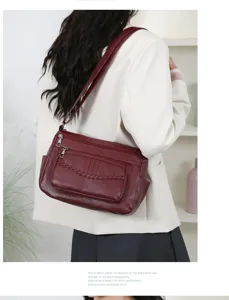 Detail view of a dark red leather crossbody bag with multi pockets and braided trim.
