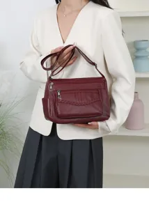 Wine red leather multi-pocket crossbody bag, detailed front braided design and zippers.