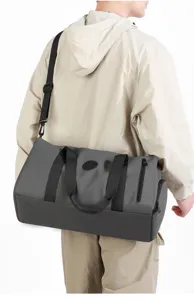 Vue détaillée du sac de voyage gris de grande capacité avec poignées et sangle robustes.