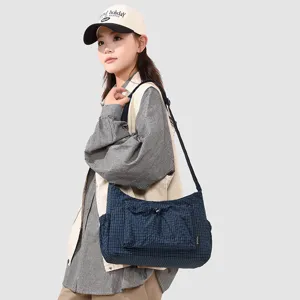 Detail view of the casual plaid shoulder bag with front drawstring pocket and adjustable strap.