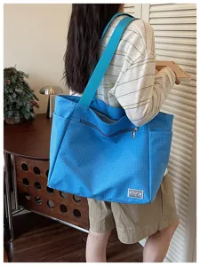 Sac cabas bandoulière en texture grille bleue avec large sangle et poche zippée quotidienne.