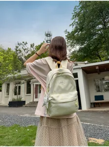 Outdoor detail view of a sweet lemon yellow tie dye student backpack with star pendant accessory.