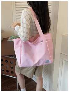 Detail de sac cabas en toile texturee rose, grande capacite et poches pratiques.