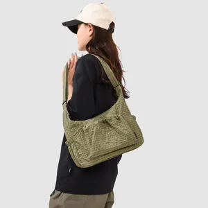 Olive green plaid shoulder bag detail with front drawstring pocket and adjustable strap design.