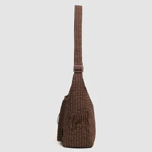 Detail view of the brown plaid shoulder bag showing adjustable strap and side pocket design.