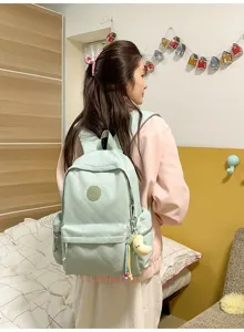 Detailed view of the light green quilted casual backpack worn by a model in a bedroom setting.