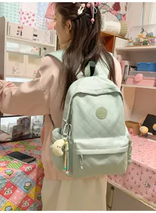 Detail shot of light green quilted backpack with cute charm and badge in sweet room setup.