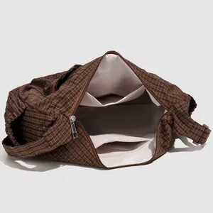 Detailed view of the brown grid shoulder bag with open interior, light lining and pockets.