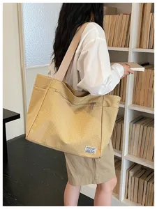 Sac cabas en toile vue detaillee avec motif carreaux, large sangle et poche avant.