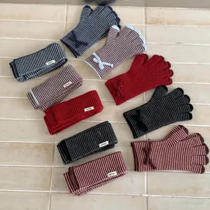 Vue détaillée de gants et bandeau tricotés rayés avec des nœuds de différentes couleurs.