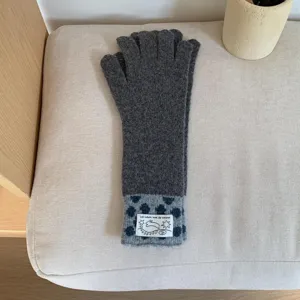 Vue détaillée de longs gants en tricot gris avec manchette à motifs et tissu chaud.