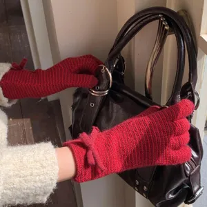 Détail rapproché de gants tricotés rouges confortables avec nœud et motif rayé élégant.