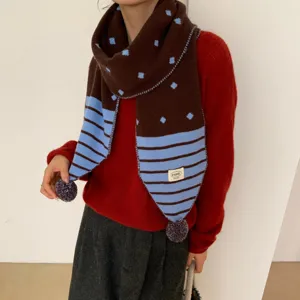 Détail d'écharpe en tricot marron avec des pois bleus, des rayures et jolis pompons.