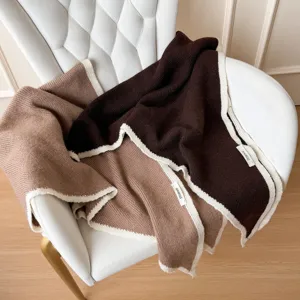 Détail de châle triangulaire en mélange de laine douce avec bord contrasté et texture.