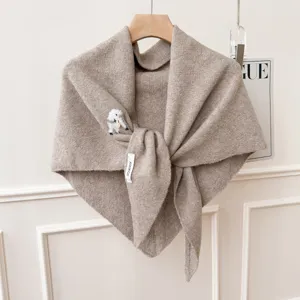 Gros plan détaillé sur l'écharpe en tricot beige douce avec broderie de chiot et texture raffinée.