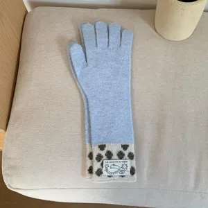 Gros plan de longs gants en tricot avec poignets à pois et étiquette tissée détaillée.