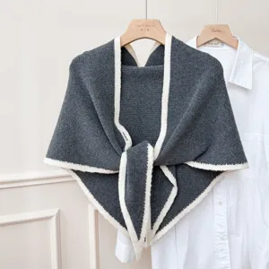 Écharpe triangulaire en tricot gris foncé avec bordure blanche, accessoire d'hiver confortable.