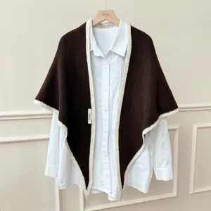 Vue détaillée du châle triangulaire en tricot marron sur une chemise blanche classique.