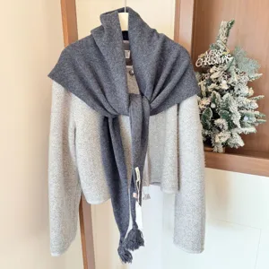Vue détaillée du châle triangulaire en laine gris foncé à franges avec son cardigan.