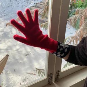 Vue détaillée de gants tricotés rouges chauds pour femmes avec poignets à pois contrastés.
