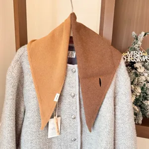 Vue détaillée de l'écharpe triangulaire en tricot de laine bicolore sur manteau à chevron.