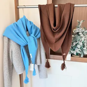 Vue détaillée d'une écharpe triangle en laine douce avec franges, suspendue sur support.