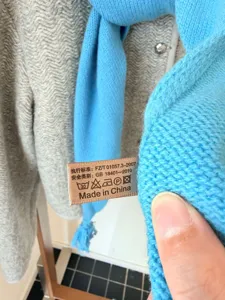 Gros plan détaillé de l'écharpe en tricot bleu mettant en valeur la texture et l'étiquette.