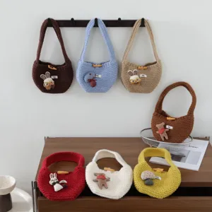 Joli sac a main en tricot mini cabas avec pendentifs en peluche et bouton en bois.