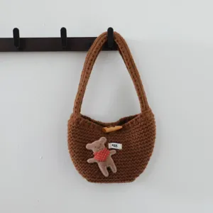 Détail du sac à main en tricot marron avec joli patch d'ours et détail de bouton corne.