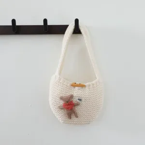 Détail de mini sac en tricot avec joli patch d'ours en peluche et bouton en bois.