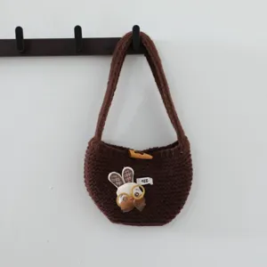 Détail de sac à main tricoté avec charmant patch de lapin et fermeture à bouton en bois.
