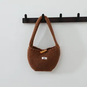 Vue de détail rapprochée du sac cabas en tricot marron montrant la texture et le bouton.