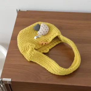 Gros plan sur un sac à main en tricot jaune avec bouton en corne et pendentif en tissu.