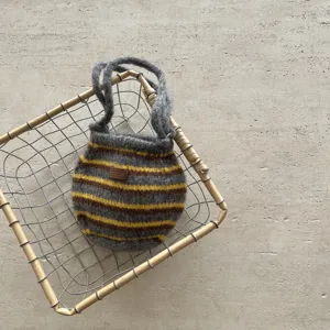 Gros plan d'un sac à main tricoté rayé élégant en gris et jaune avec de la laine texturée.