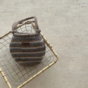 Vue détaillée d'un sac à main tricoté rayé confortable aux couleurs contrastées et étiquette.