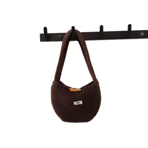 Sac à main tricoté marron avec fermeture en bois et petite étiquette, style chic pour tous les jours.