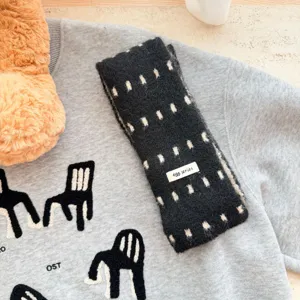 Vue détaillée de l'écharpe en tricot noir avec des points blancs et un design doux.