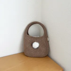 Sac à main en tricot marron confortable avec un joli pompon duveteux pour l'automne et l'hiver.