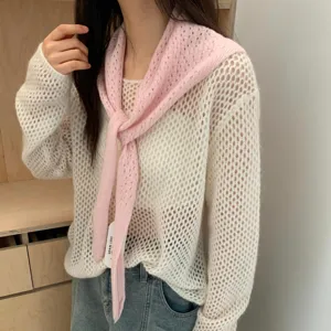 Détails élégants du foulard triangulaire en tricot rose et du pull en-dessous.