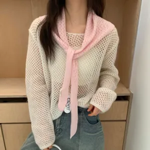 Détail de foulard triangulaire en maille rose et haut ajouré blanc, texture douce.