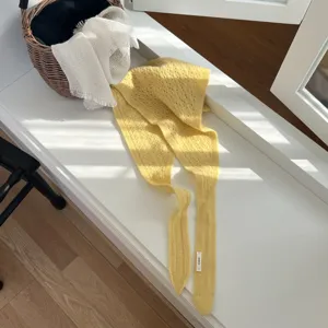Détail écharpe triangulaire ajourée en tricot jaune, motif résine pour hiver élégant.