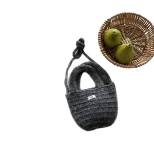 Grey knitted crossbody phone bag with knotted strap and chic basket prop studio photo