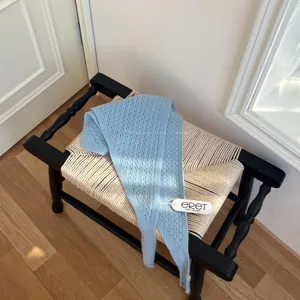 Vue détaillée d'écharpe triangulaire en tricot ajouré bleu clair, douce pour l'hiver.