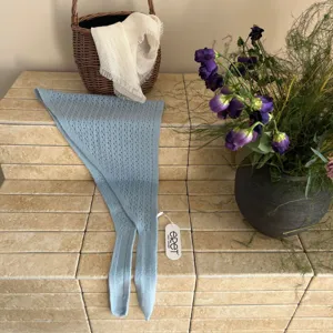 Détail d'écharpe triangulaire ajourée en tricot bleu clair, texture douce et fin.