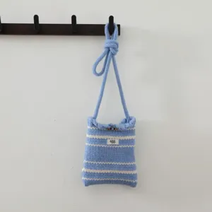 Détail de sac bandoulière en tricot rayé, mini pochette pour téléphone très tendance.